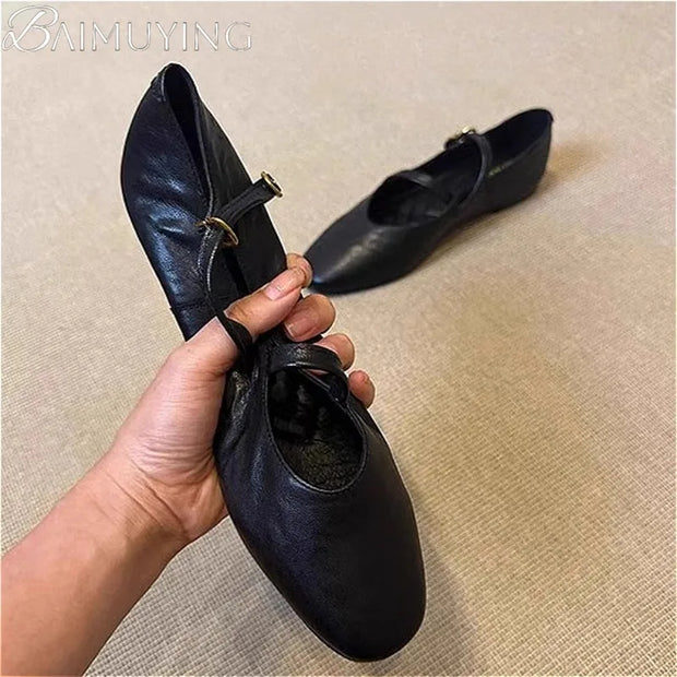 A hand holding a black leather Flats Mary Jane Shoes, showcasing the ankle strap and retro design.